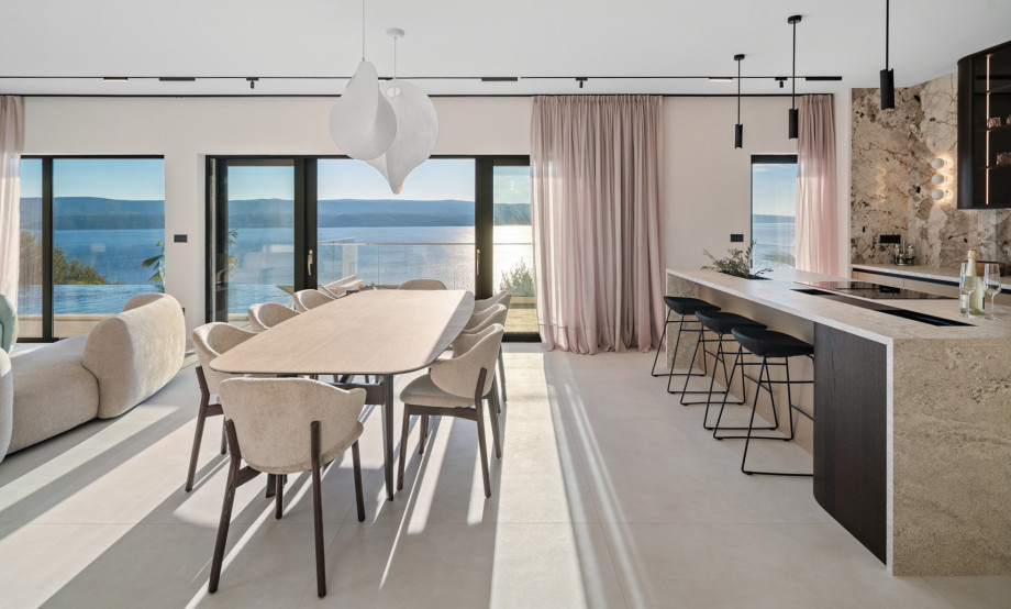 The indoor living and dining area features a stylish dining table and a fully equipped kitchen with a large island.