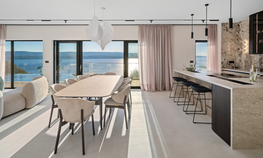 The indoor living and dining area features a stylish dining table and a fully equipped kitchen with a large island.