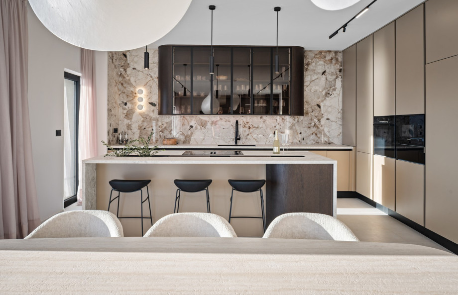 The fully equipped kitchen features a large kitchen island with bar stools, situated near the elegant dining table.