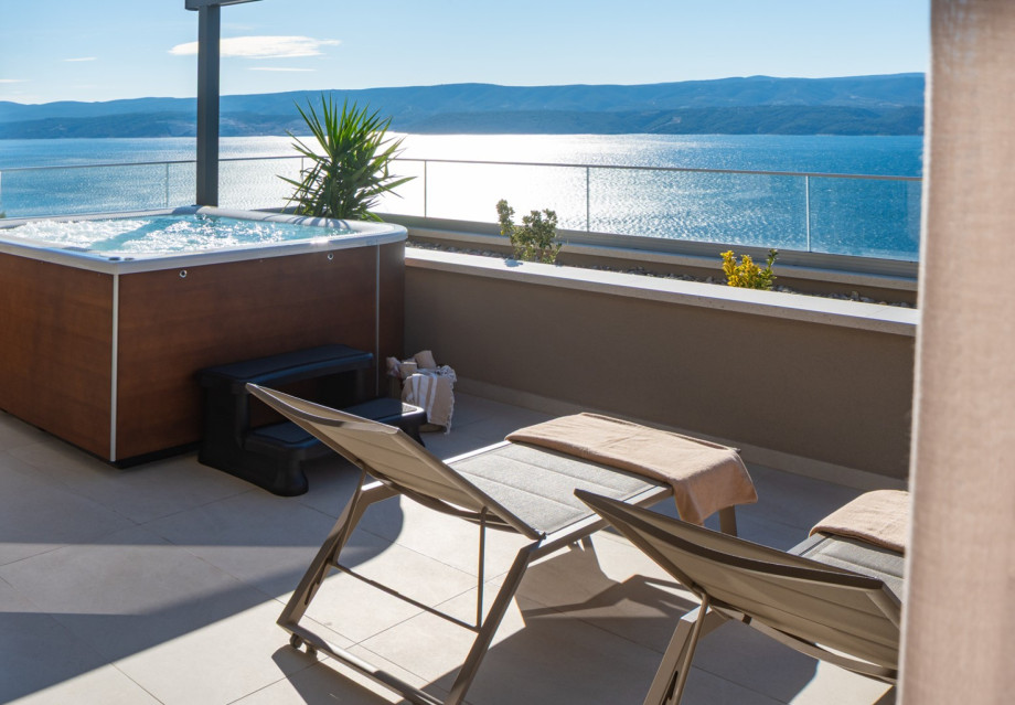 The master bedroom's private terrace features a hot tub (whirlpool), deck chairs, and spectacular sea views.
