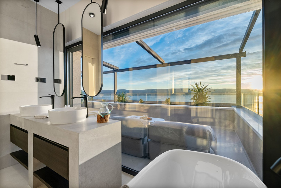 The en-suite bathroom of the master bedroom includes double sinks and views out to the private terrace with the hot tub.