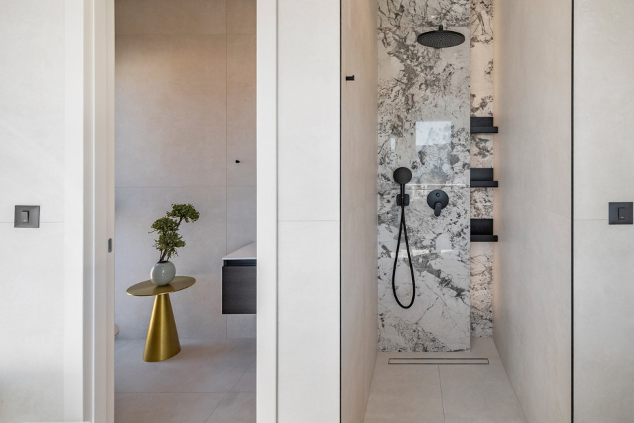 One of the modern en-suite bathrooms features a stylish walk-in shower with a contrasting marble wall finish.