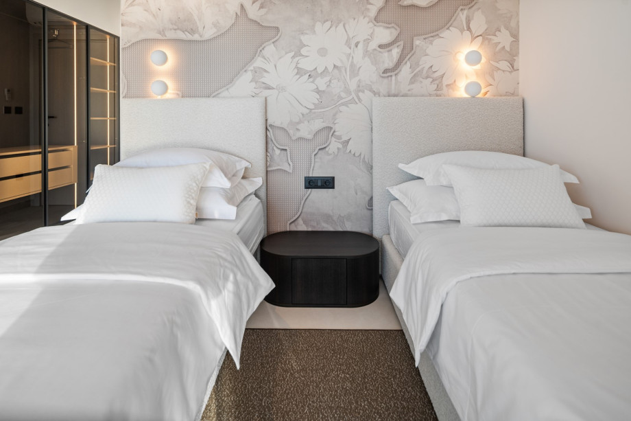 This image captures a bedroom with its two single beds that can be connected into a king-size bed.