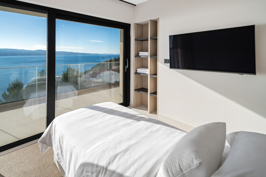 This stunning bedroom boasts spectacular sea views from the large floor-to-ceiling glass sliding doors.