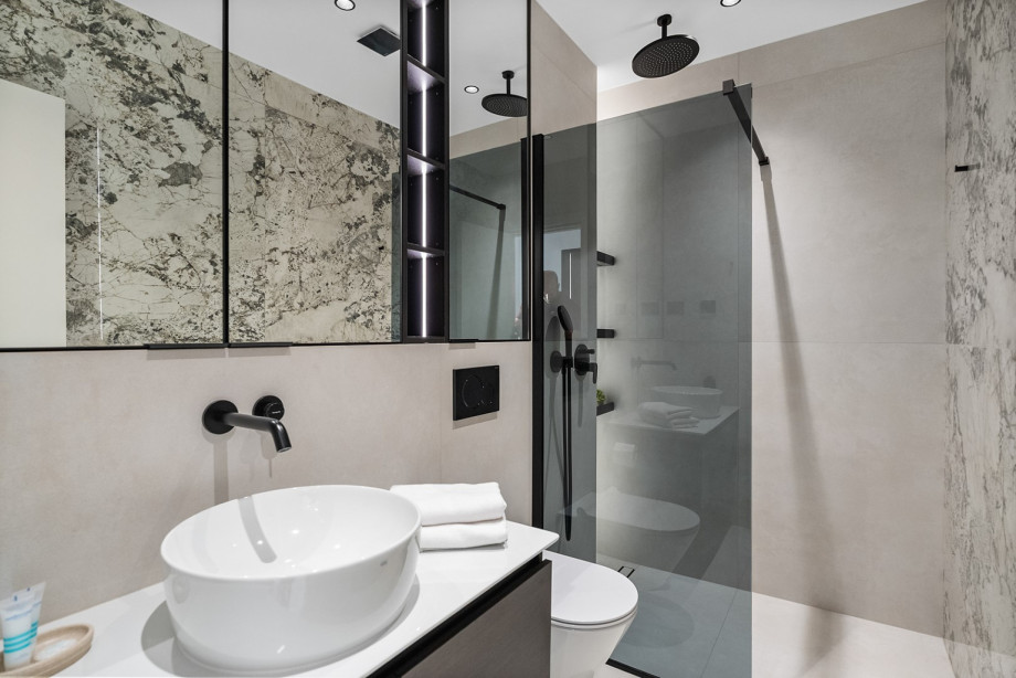 One of the villa's modern en-suite bathrooms features a large sink, marble accents, and a walk-in shower with a rain showerhead.