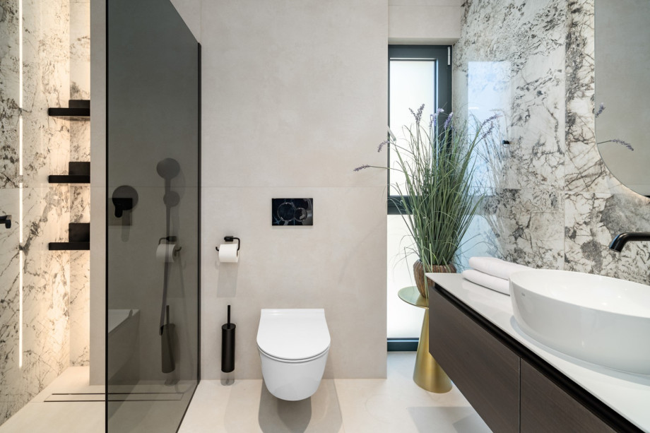 This en-suite bathroom shows a toilet, a shower area, a vessel sink, and black-framed glass separation, equipped with all modern amenities.