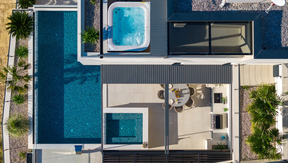 This is an aerial view of the outdoor area, featuring the private, heated infinity pool with its attached hydromassage area and the separate Jacuzzi (Whirlpool) on the upper terrace.