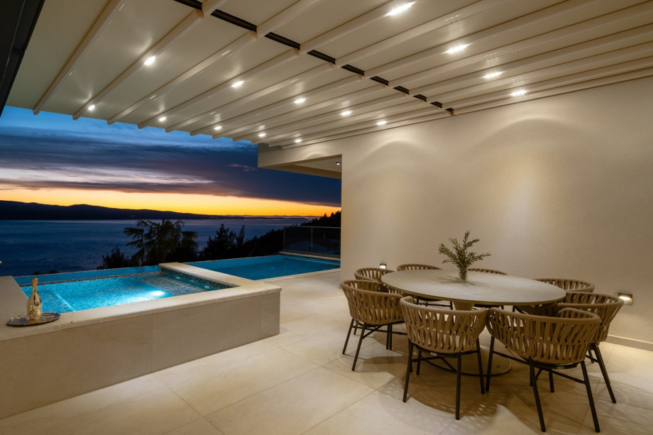 The covered outdoor dining area, seating ten people, offers views of the sea and the infinity pool.