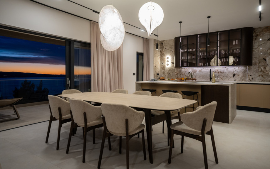 The indoor living and dining area features a stylish dining table and a fully equipped kitchen with a kitchen island.