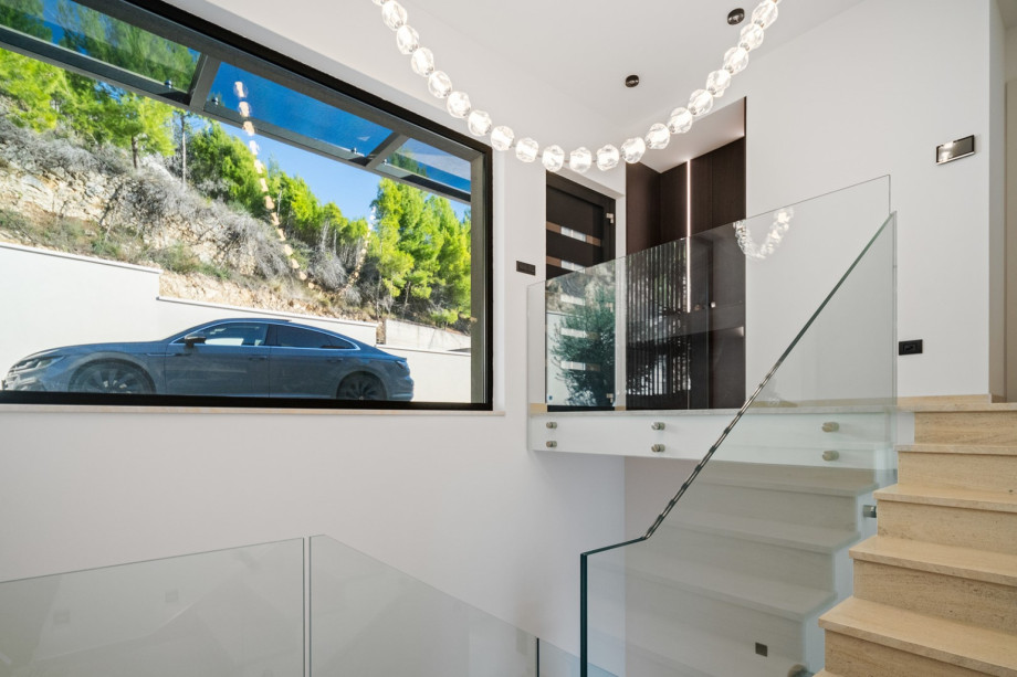 The main entrance area features an indoor staircase and a window view, offering a glimpse of the parking area.