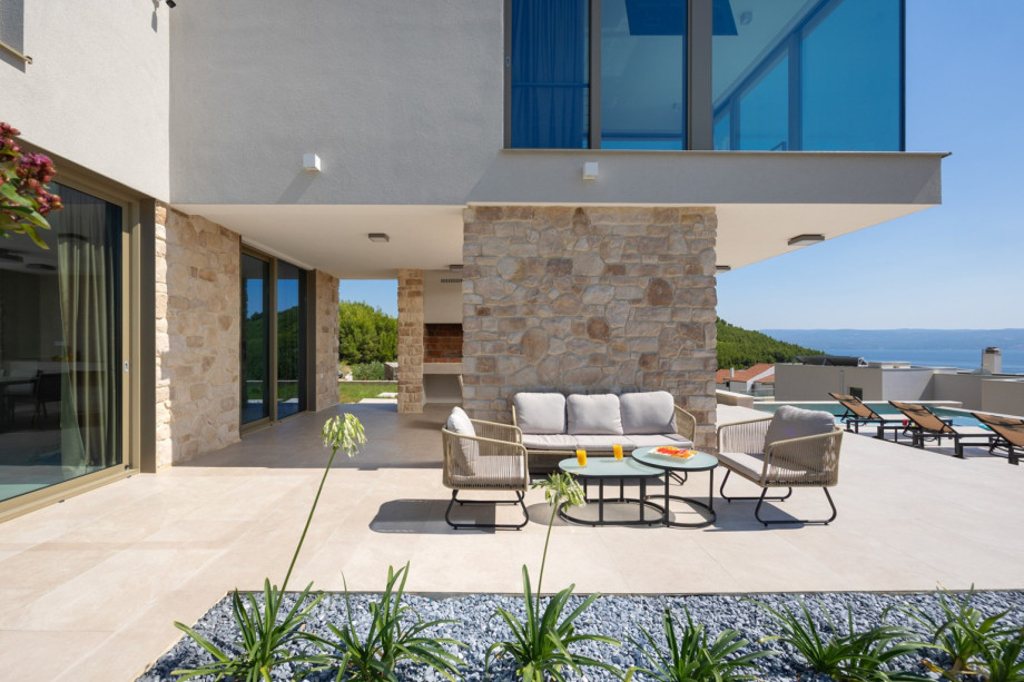 The outdoor area features a comfortable lounge corner, offering a relaxing spot adjacent to the private pool.