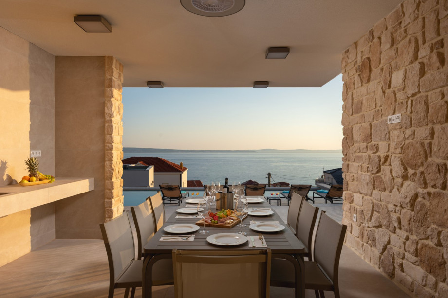 Enjoy alfresco dining in the covered outdoor area with a barbecue, offering magnificent sea and neighborhood views.