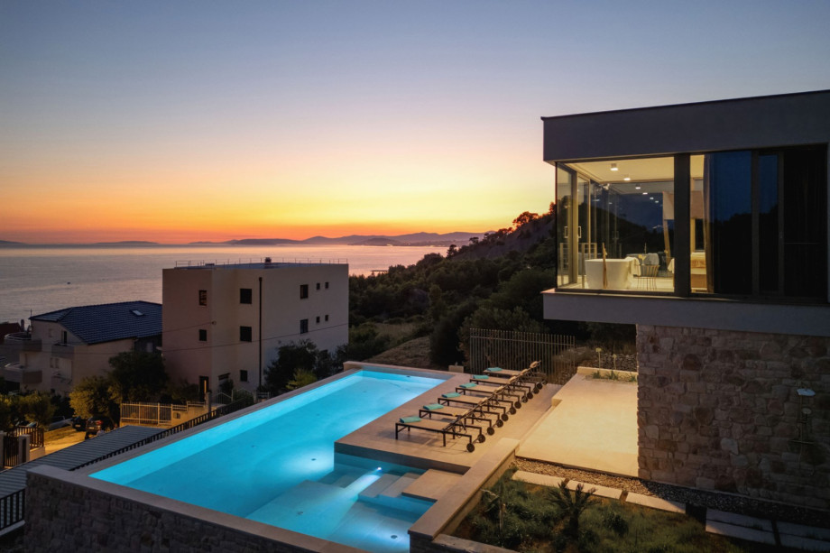 View of the pool and the luxurious upstairs Bedroom 1 (30 sqm), featuring a freestanding bathtub visible through the glass wall.
