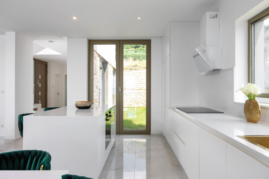View of the fully equipped kitchen, which features an island and leads to the hallway and exterior.
