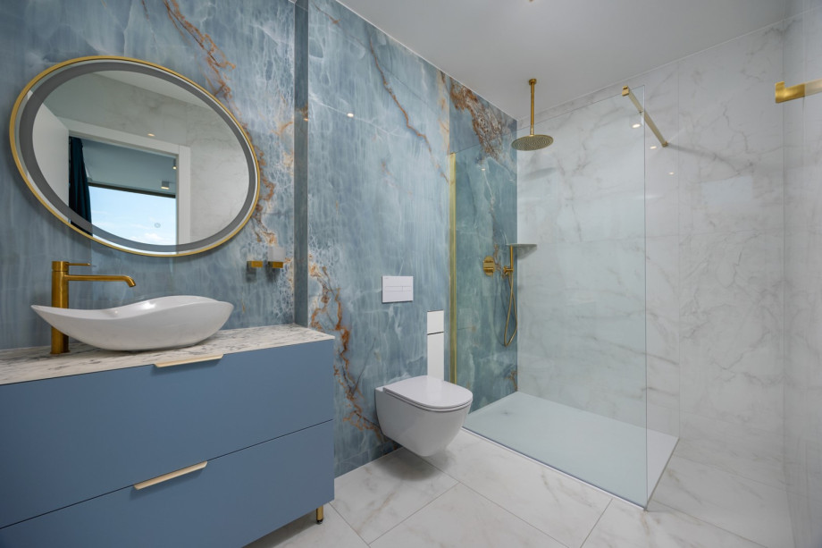 An elegant en-suite bathroom with a shower and stylish blue-and-marble accents.
