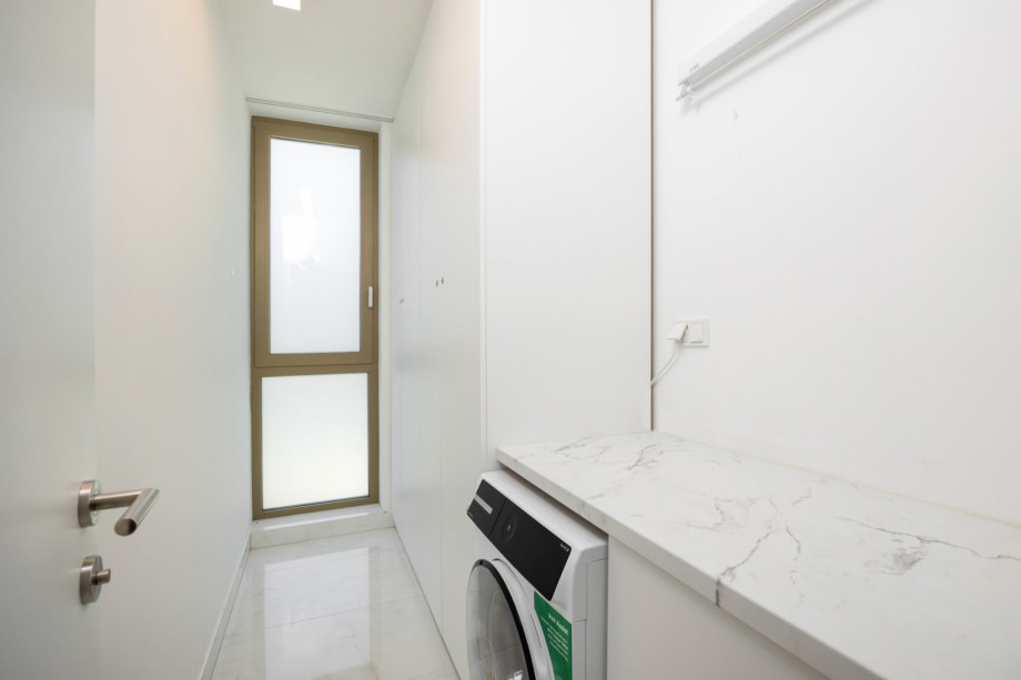 The hallway includes a convenient laundry area with a washing machine and ironing facilities.