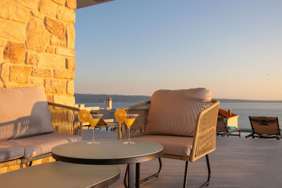 Outdoor lounge corner on the terrace with comfortable seating, perfect for watching the sunset over the sea.