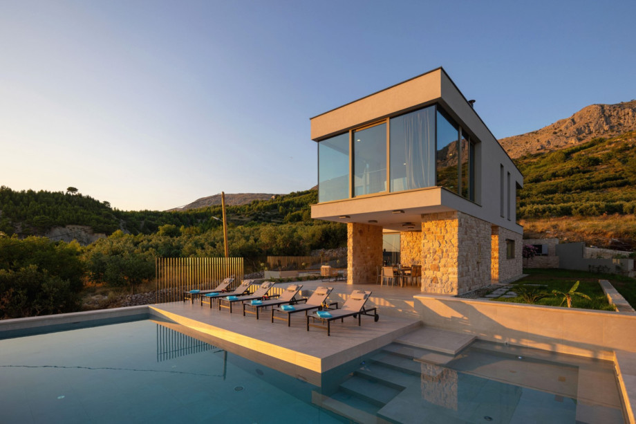Modern villa design featuring a private heated pool and sun deck set against the beautiful mountainside.
