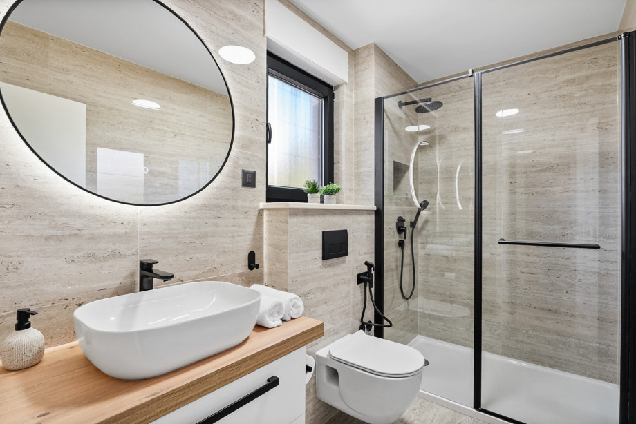 Elegant en-suite bathroom featuring a large round mirror and a spacious walk-in shower.