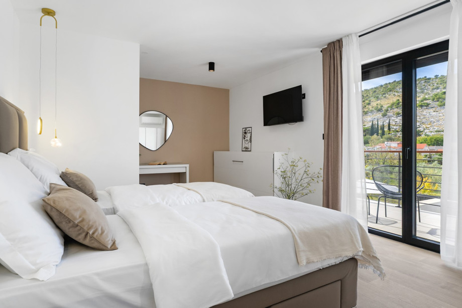 Light-filled bedroom featuring twin beds and direct access to a balcony with peaceful views.