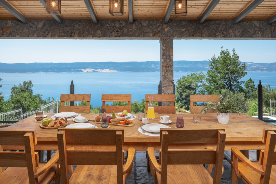 Large covered patio complete with a kitchen island, grill, outdoor dining set, and lounge