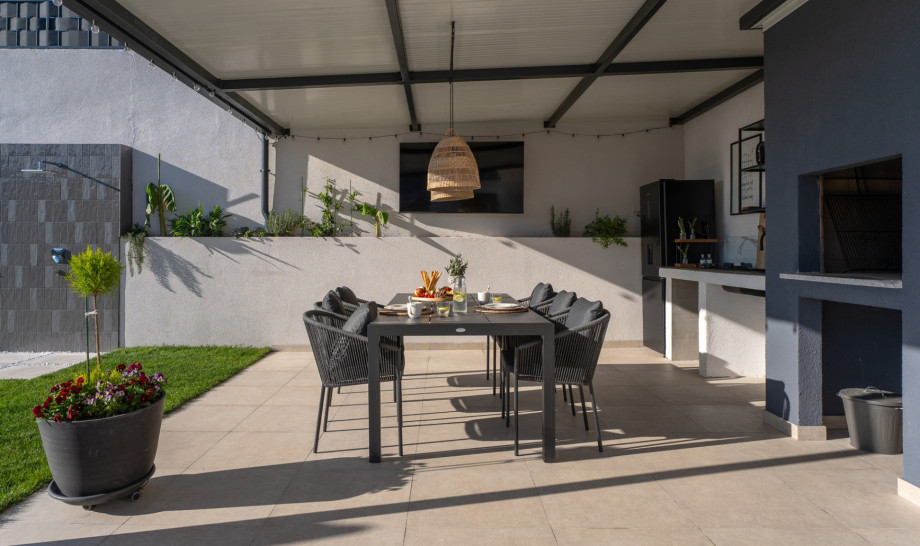 Covered al fresco dining in the fully equipped summer kitchen with a TV and traditional barbecue.
