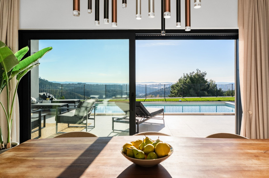The contemporary dining table is close to glass doors that seamlessly open to the pool area.