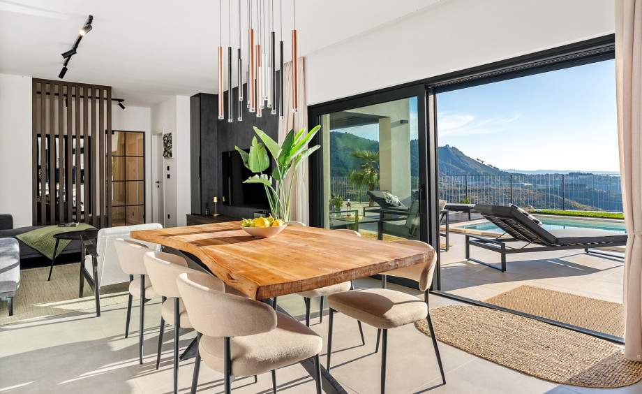 The contemporary dining table with natural wood finish, opening to the pool and scenic mountain views.