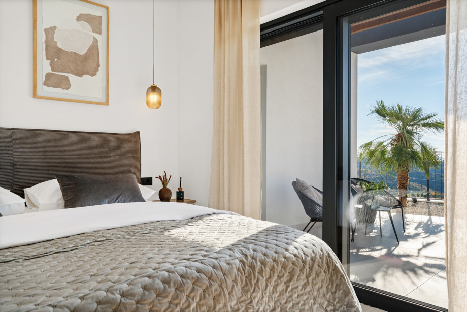 Bedroom 2 with relaxing chairs on the terrace and lovely views overlooking the mountains.