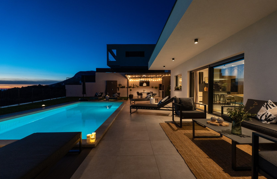 Night view of the villa exterior, highlighting the pool and the charming lounge corner for relaxing.