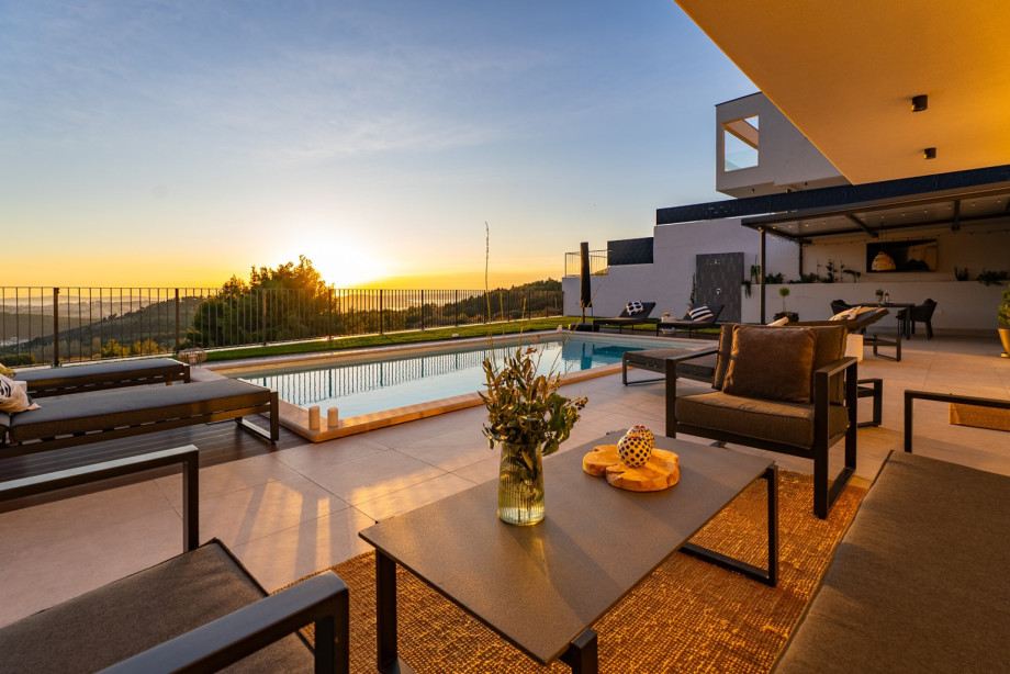 The charming lounge corner by the pool, bathed in the warm light of the sunset.