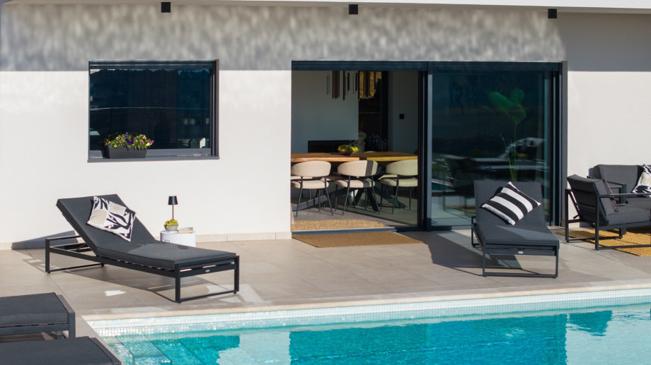 Sun loungers near the pool and the sliding glass door access to the indoor dining area.