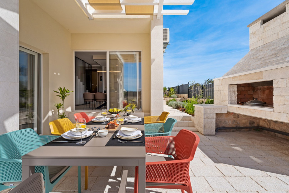 An outdoor dining area with a traditional grill (wood/charcoal)