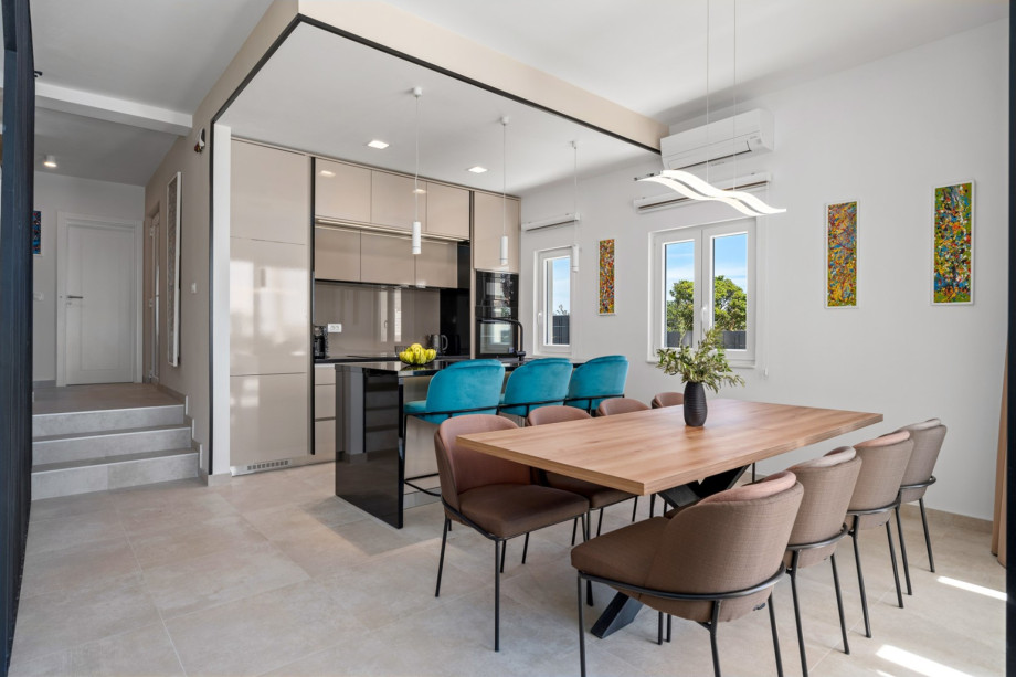 Kitchen island with 3 chairs, a dining table for 8, a step lower is a living room