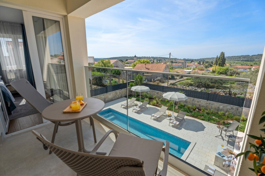 Bedroom NO2  with a balcony with two chairs and a table, and views of the pool and the village.