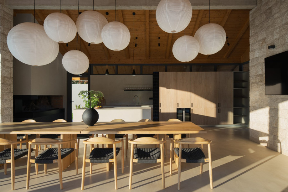 The stylish interior has a long wooden table and a sleek, high-end summer kitchen.