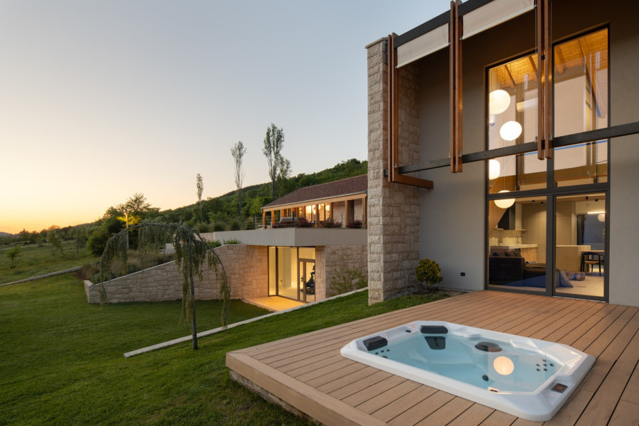 Modern design meets traditional stone, featuring a sleek outdoor whirlpool and expansive terrace views.