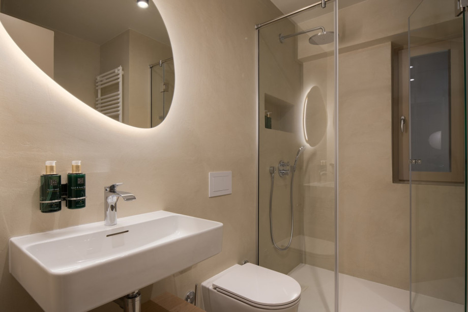 One of the 10 luxury bathrooms features a rainfall shower, an ambient backlit mirror, and premium finishes.