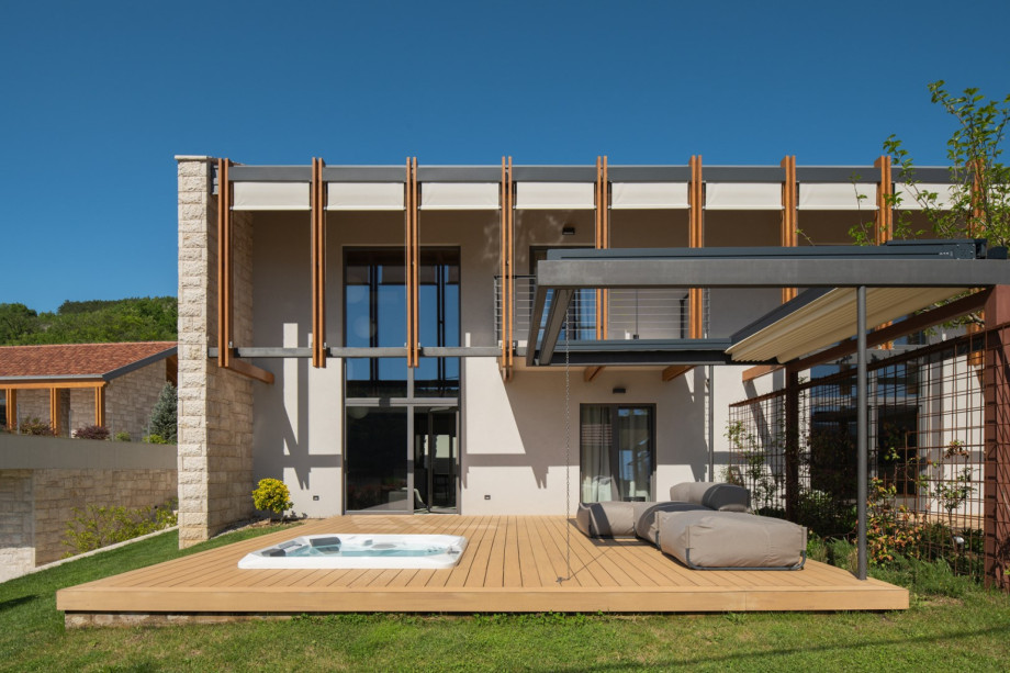 The villa’s exterior shows a spacious terrace with a whirlpool and a retractable awning for relaxation.