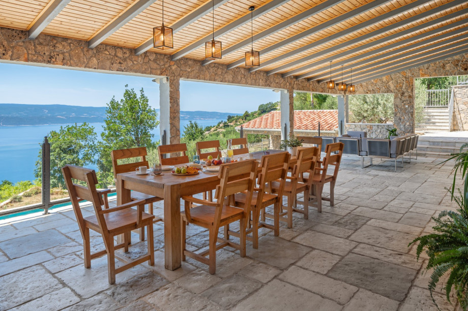 Large covered patio complete with a kitchen island, grill, outdoor dining set, and lounge
