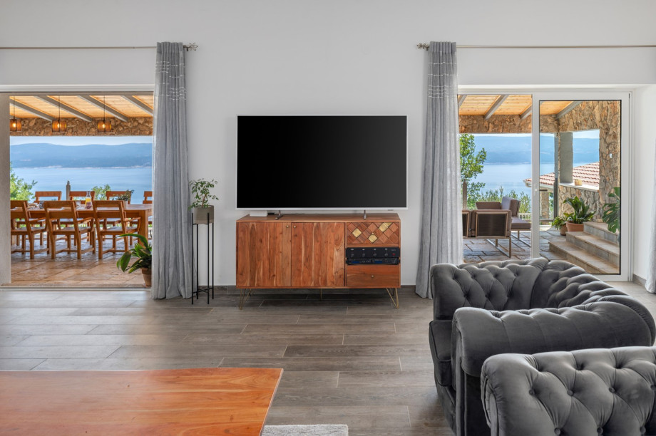 Living room with sofas,a reading/working corning, a flat screen TV, and doors toward the outdoors