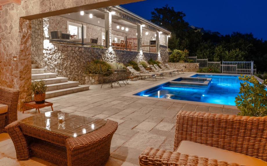 Large covered patio complete with a kitchen island, grill, outdoor dining set, and lounge.