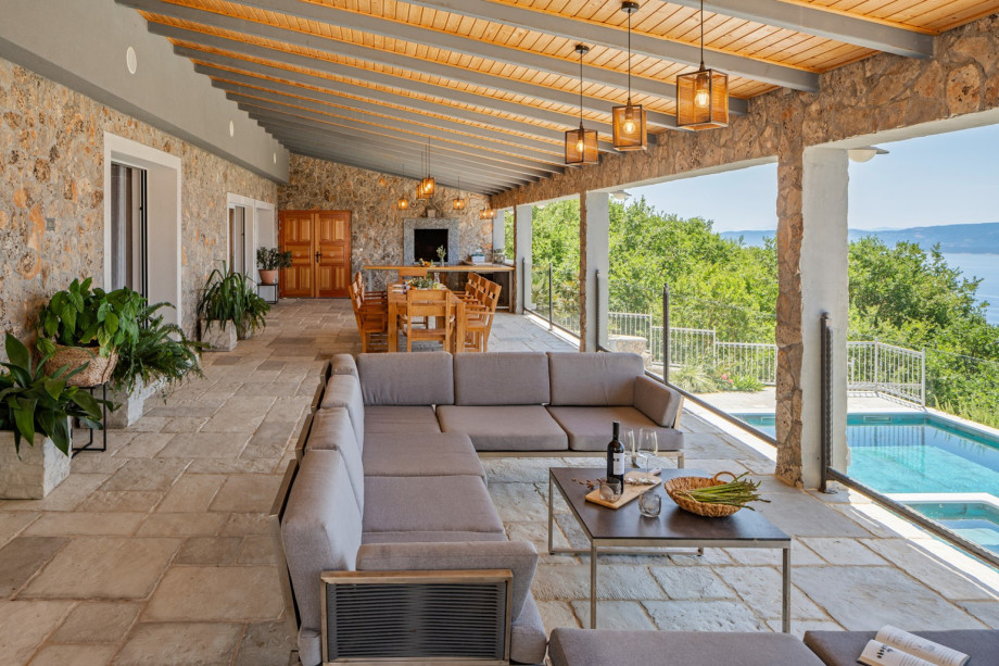 Large covered patio complete with a kitchen island, grill, outdoor dining set, and lounge