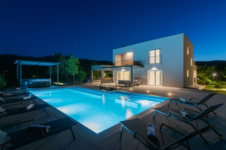 The 66 sqm heated pool with hydromassage jets offers a direct view of the modern 230 sqm villa.