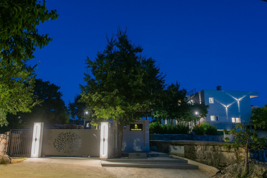 The villa is situated on a fenced 1,900 sqm private plot with an illuminated gated entrance.