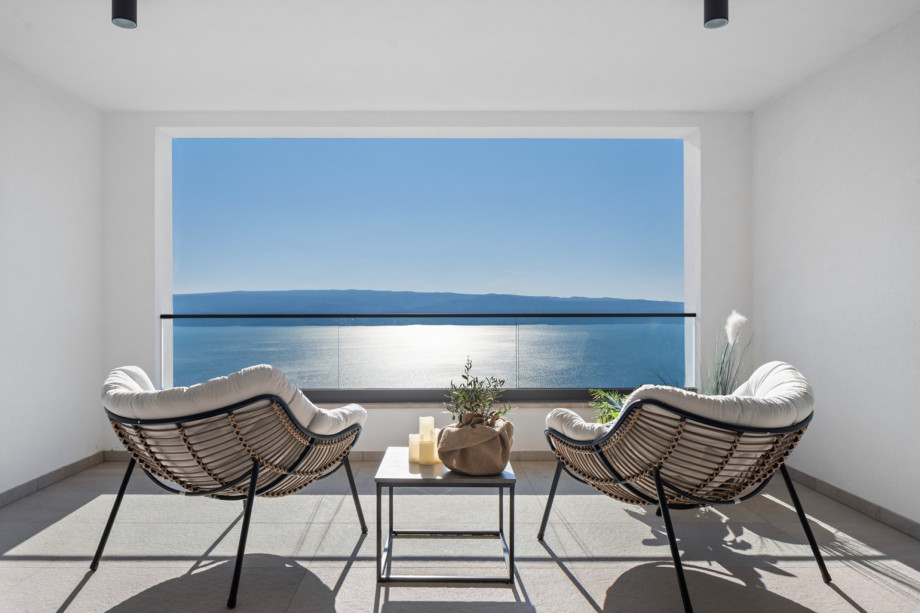 The private balcony features two chairs and stunning views of the sea.