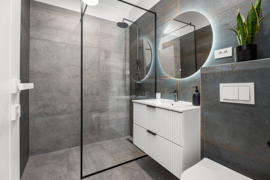 Modern en-suite bathroom equipped with a shower and stylish fixtures.