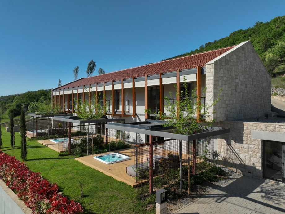 The villa’s modern facade features private wooden decks equipped with individual hot tubs for every unit.