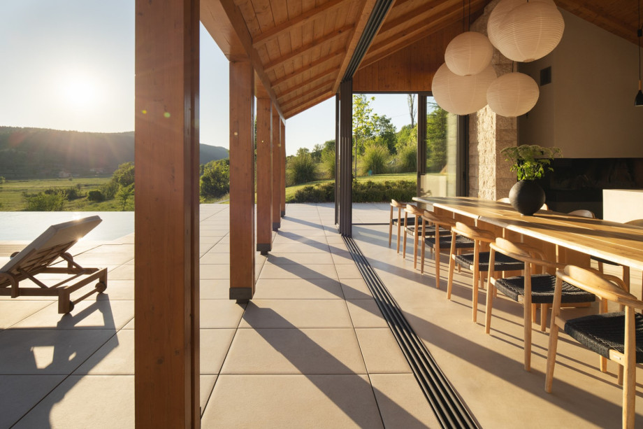 Sunlit terrace view showing the covered dining area next to the heated pool and outdoor seating.
