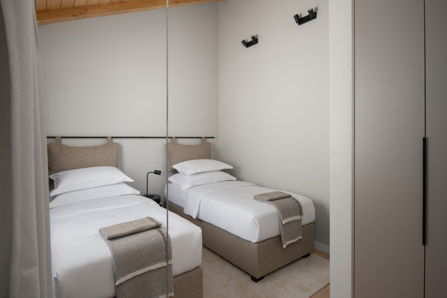 One of 9 beautifully appointed bedrooms, featuring plush twin beds and contemporary lighting.